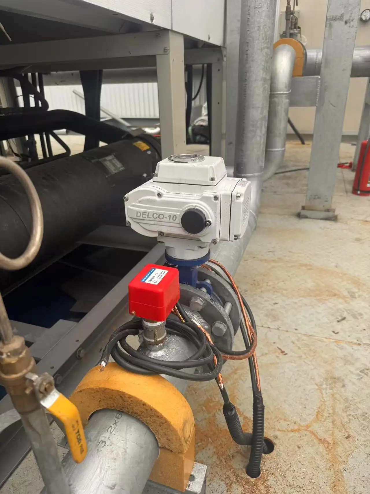 DELCO-10 electric actuated butterfly valve installed on a chilled water pipeline near automated pressure switches.